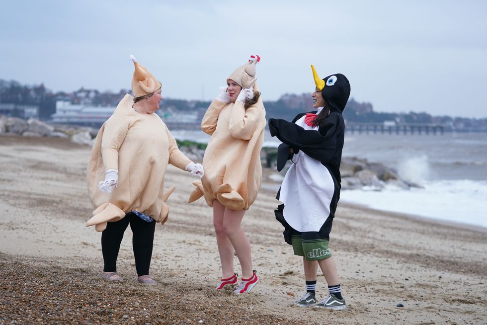 Disappointed swimmers dressed as turkeys and a penguin stand on the beach in Felixstowe, Suffolk, where the Christmas Day dip has been called off due to adverse weather. Picture date: Saturday December 25, 2021.