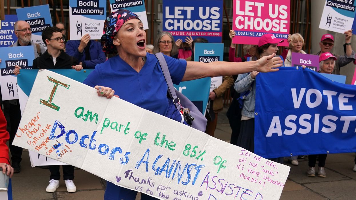 Doctor Geri Hignett protests against a change in the law on assisted dying, beside protesters demonstrating in support, outside the Scottish Parliament in Edinburgh