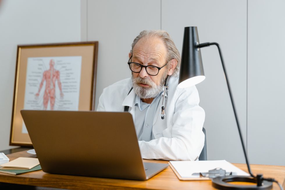 Doctor looks at laptop in office