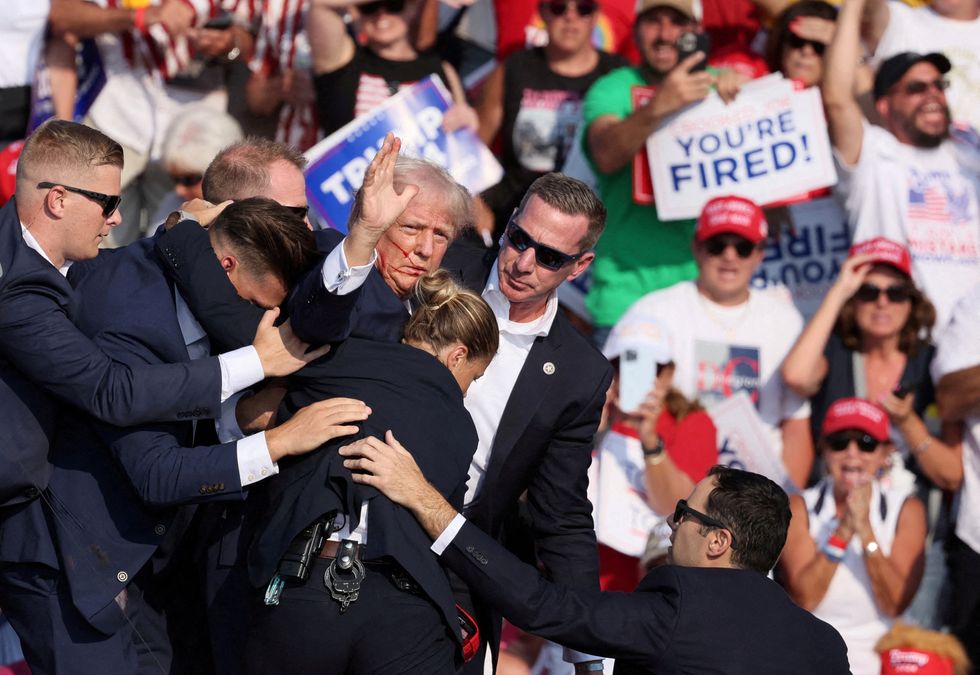 Donald Trump gestures with a bloodied face after being shot at a rally