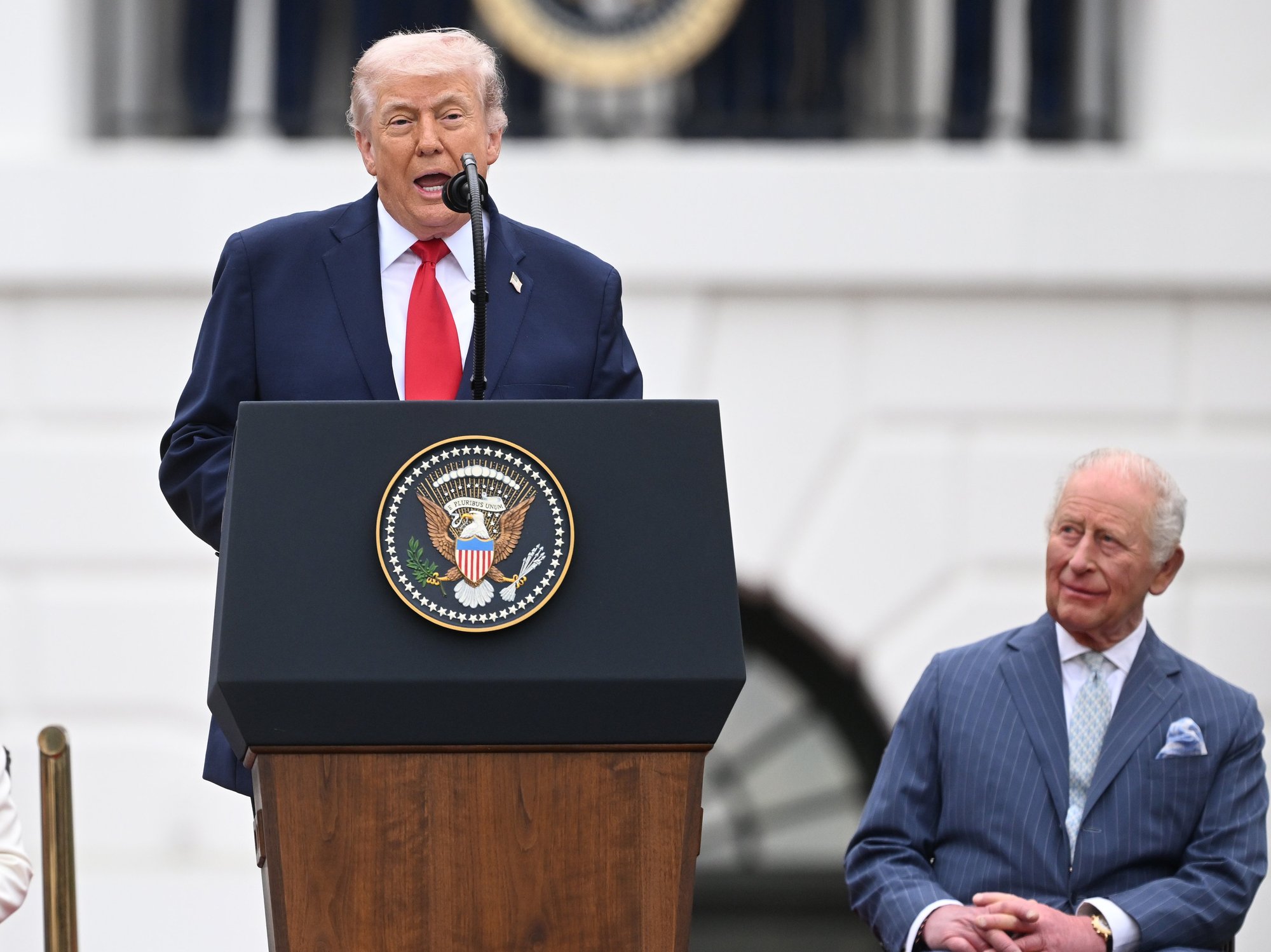 Donald Trump giving a speech on the White House lawn in front of King Charles and Queen Camilla
