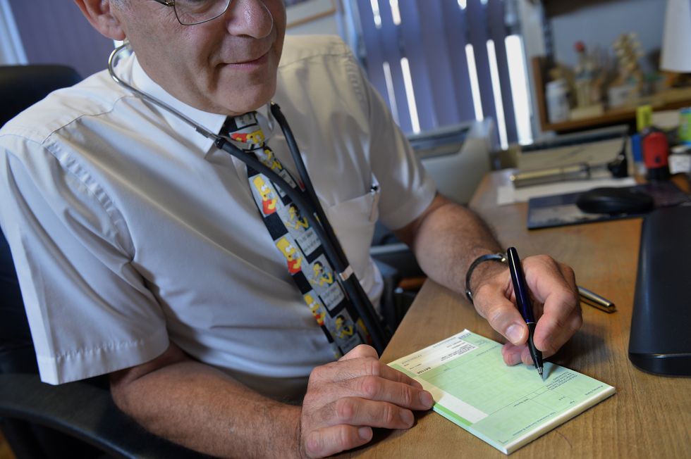 Dr Laurence Buckman writes a prescription in his practice room at the Temple Fortune Health Centre GP Practice near Golders Green, London.