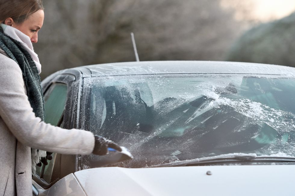 Driver clearing frost from car windscreen