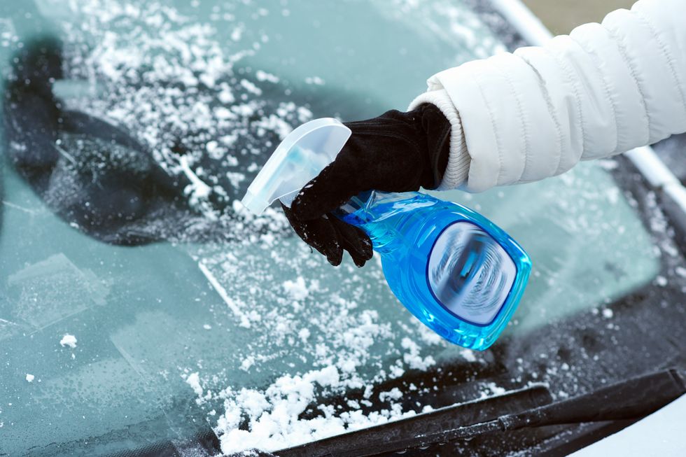 Driver spraying de-icer on their windscreen