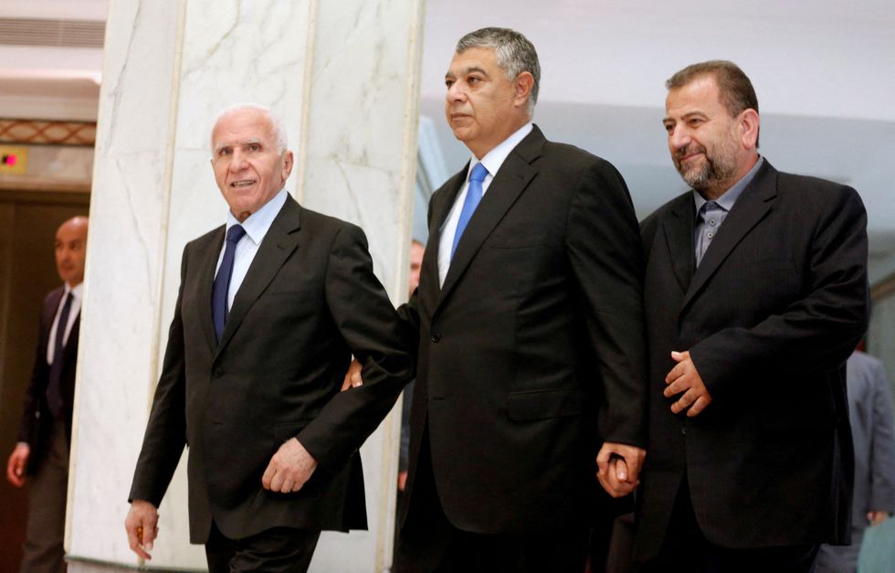 Egyptian intelligence chief Khaled Fawzi walks with head of Hamas delegation Saleh al-Arouri and Fatah leader Azzam Ahmad as they sign a reconciliation deal in Cairo, Egypt, October 12, 2017.