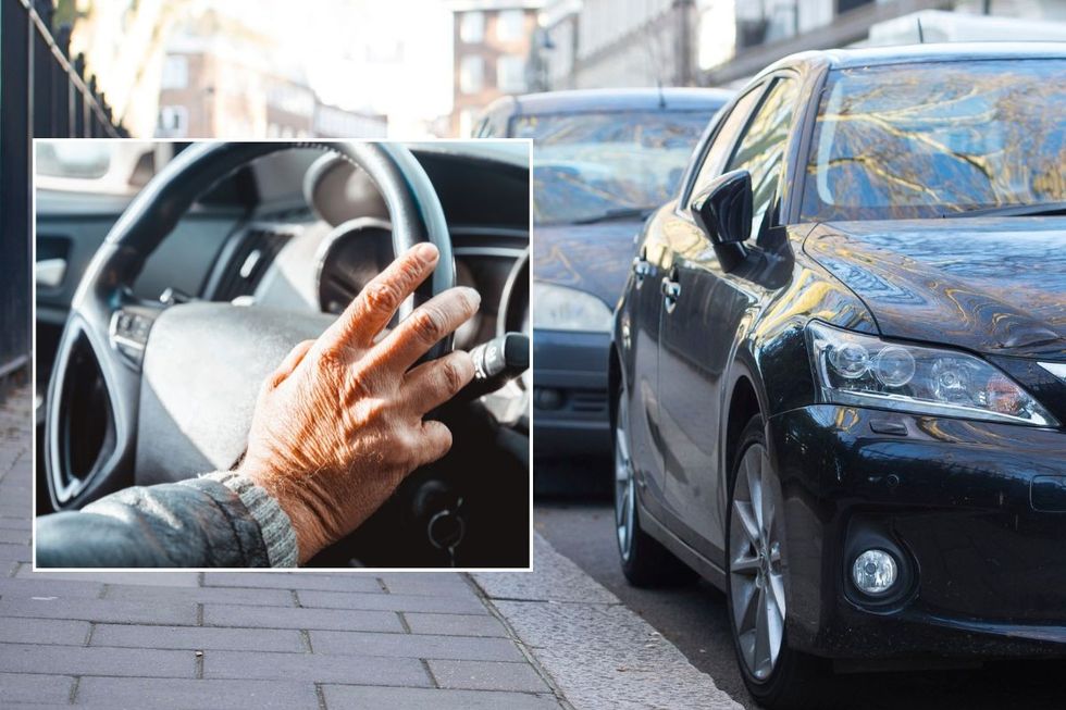 Elderly hand on a steering wheel and a row of cars parked on a road
