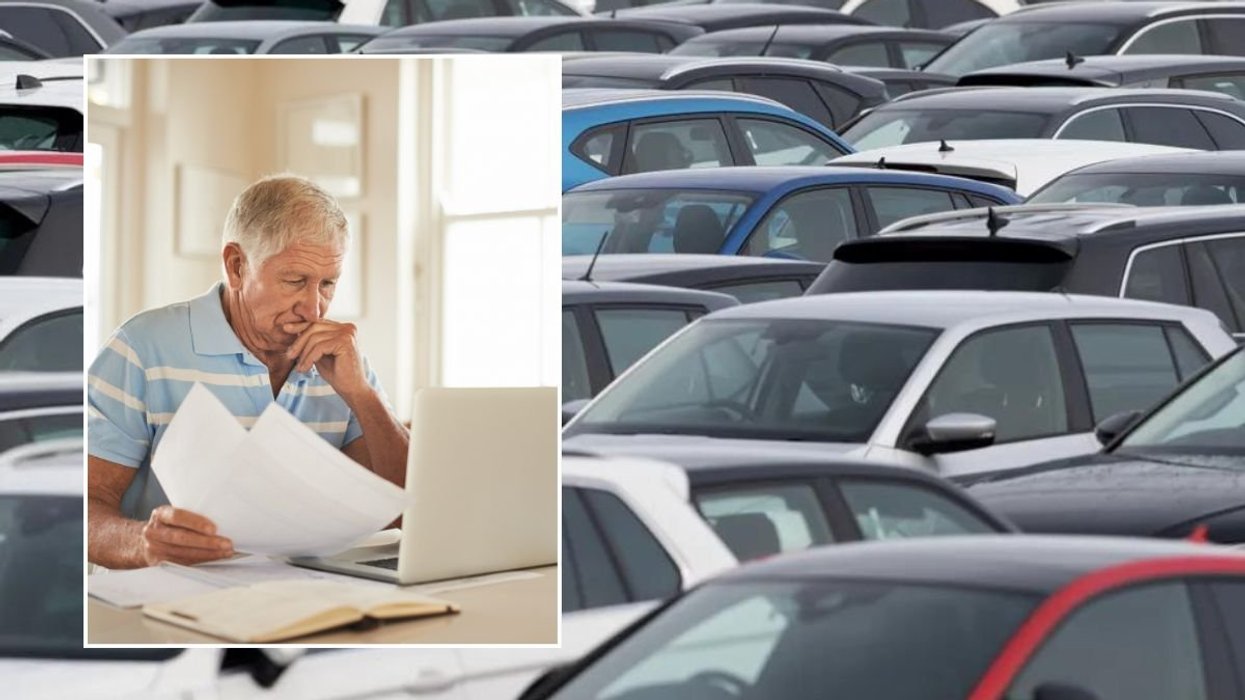 Elderly man checking his laptop and cars parked