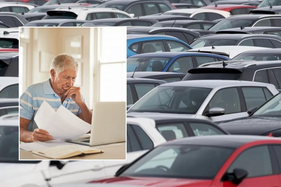 Elderly man checking his laptop and cars parked
