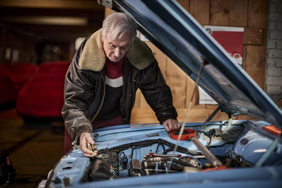 Elderly man fixing car