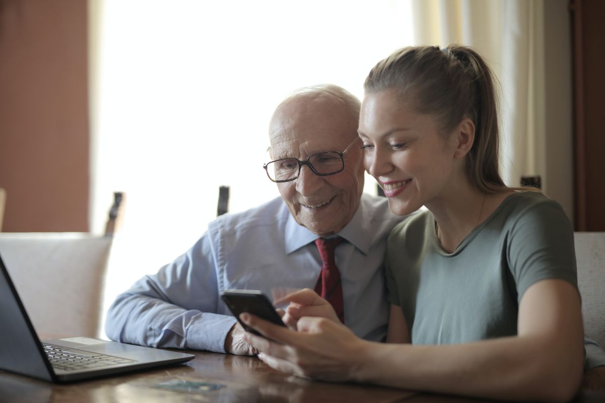 Elderly man looking a phone with a woman