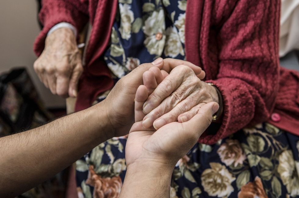 Elderly woman holding loved ones hand