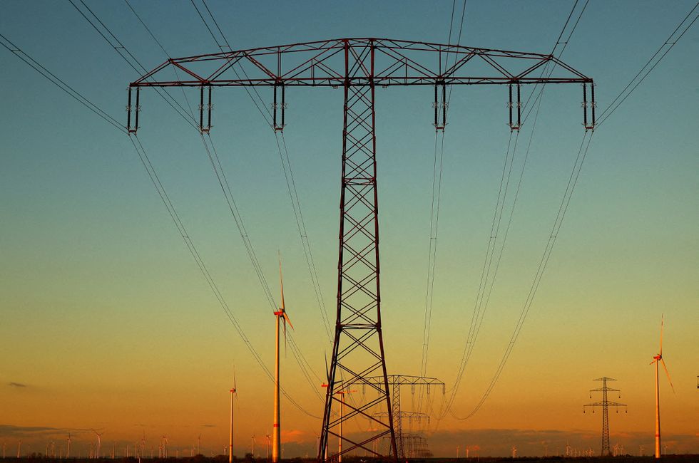 Electrical power pylons with high-voltage power lines are seen next to wind turbines near Weselitz, Germany