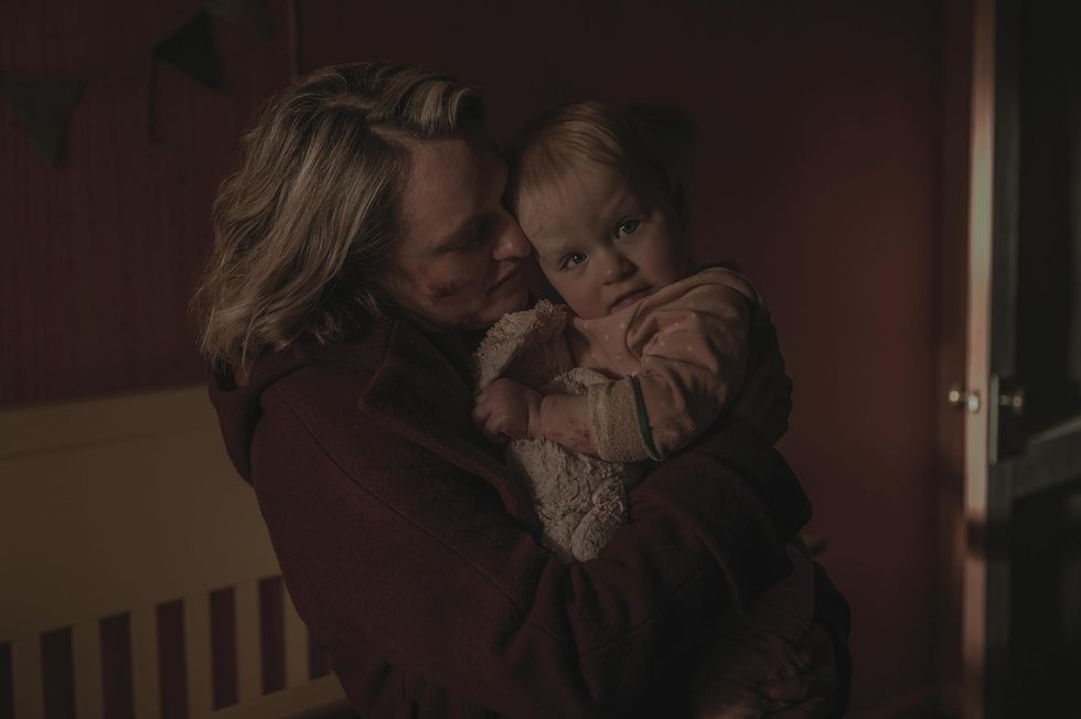 elizabeth moss holding a baby in a scene from the handmiads tale