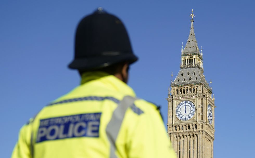 Elizabeth Tower, part of the Palace of Westminster, is seen with a Metropolitan Police officer in Parliament Square, London. Picture date: Saturday March 19, 2022.