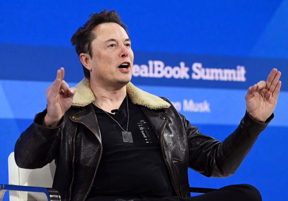 Elon Musk pictured in a leather flight jacket speaking at a conference about social media