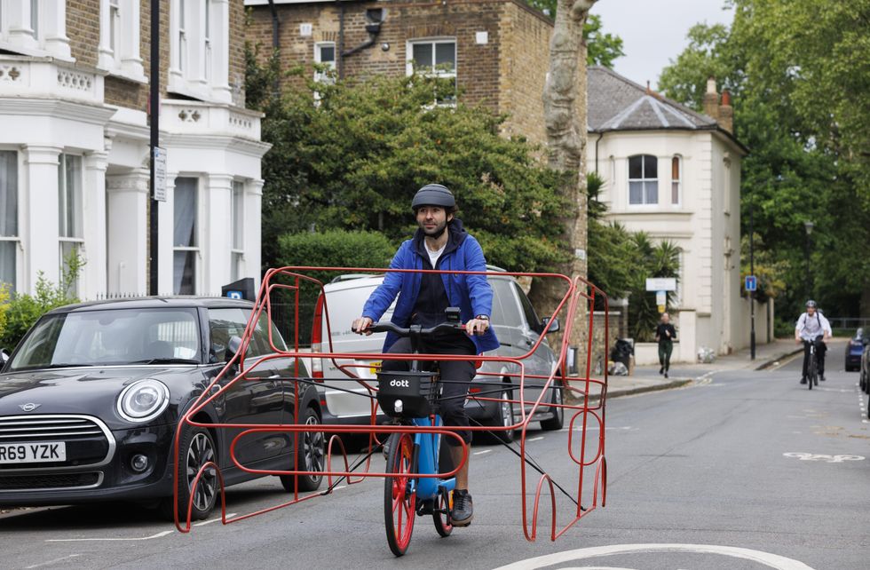 EMBARGOED TO 0001 TUESDAY MAY 31 Undated handout photo issued by Dott of a cyclists wearing a frame shaped like a car to demonstrate that vehicles are %22hogging%22 roads. Issue date: Tuesday May 31, 2022.