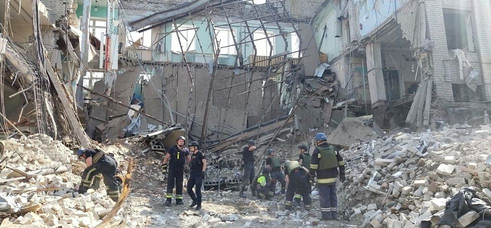 Emergency service members work at a site of an apartment building heavily damaged by a Russian missile strike