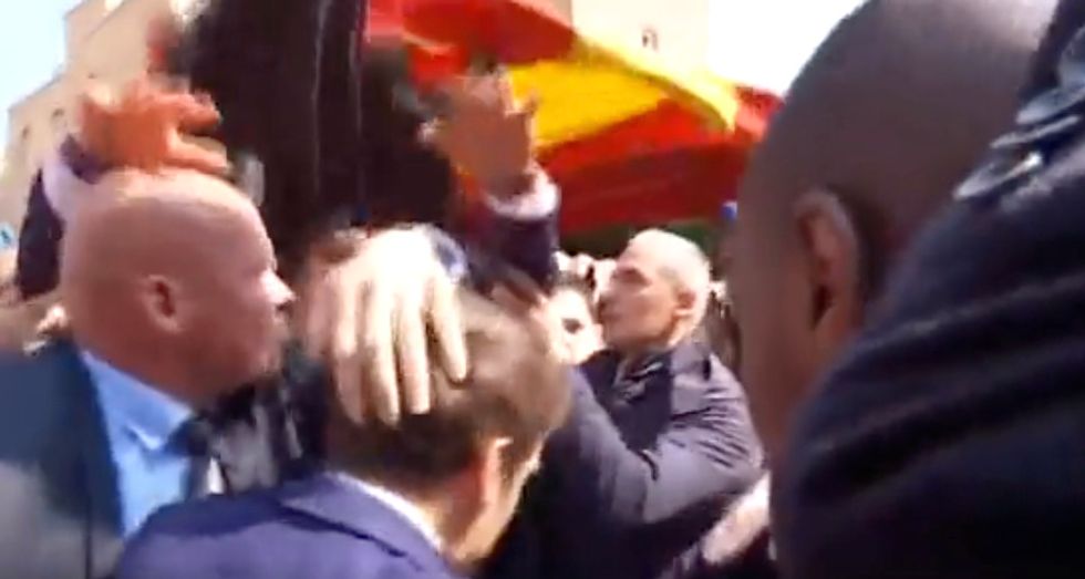 Emmanuel Macron's security team quickly deployed an umbrella to shield the French president from flying tomatoes.