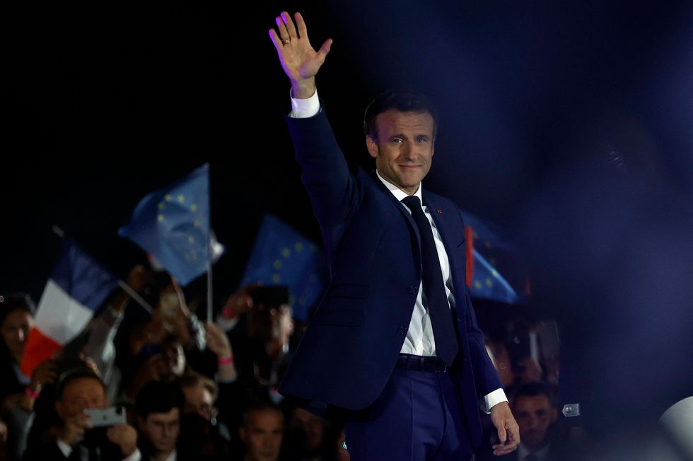 Emmanuel Macron waves on stage after winning re-election.