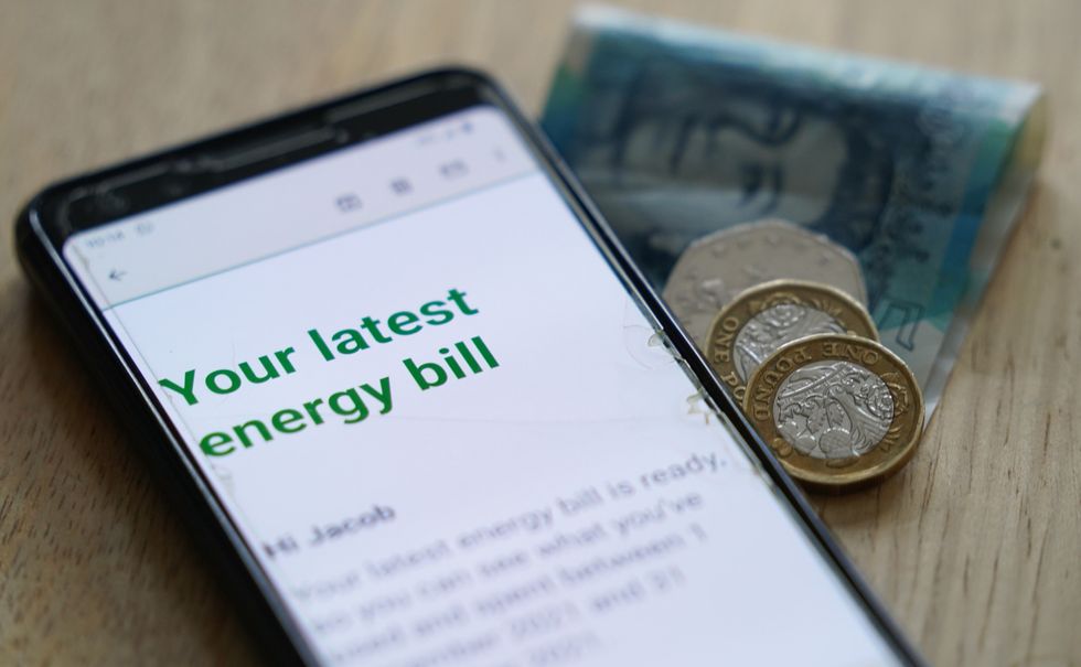 Energy bill on mobile phone and cash beside it