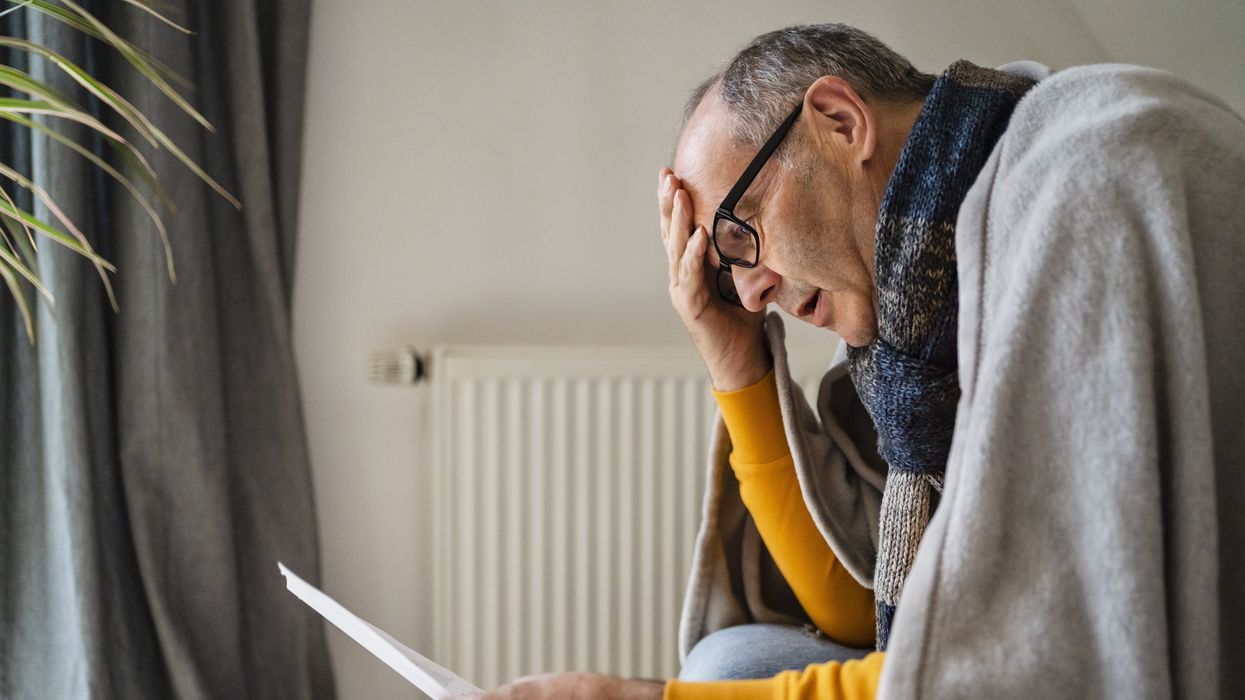 Energy bills statement being read by man under blanket