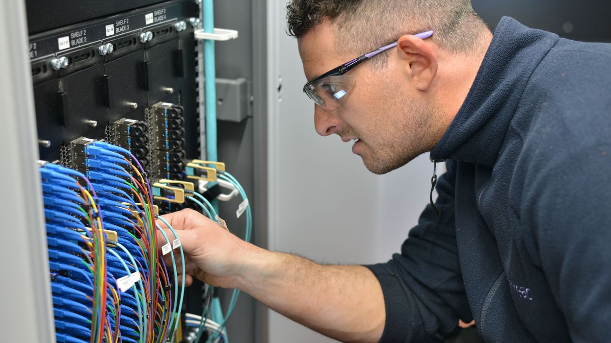 engineer fits cables into a cabinet to connect broadband