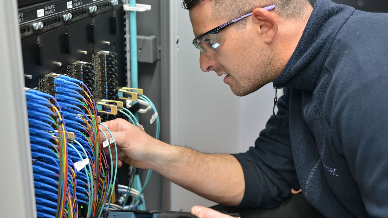 engineer fits cables into a cabinet to connect broadband