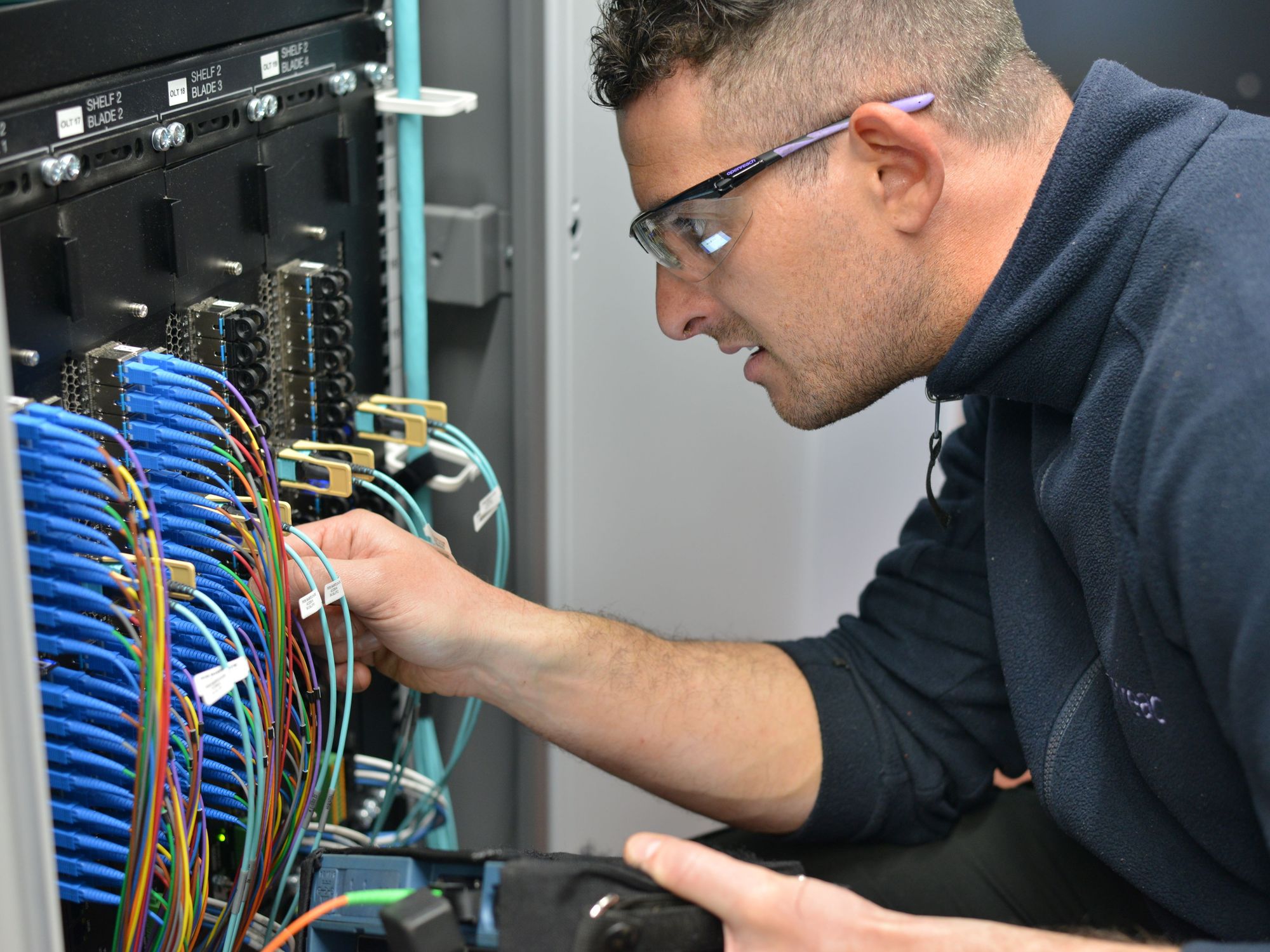engineer fits cables into a cabinet to connect broadband