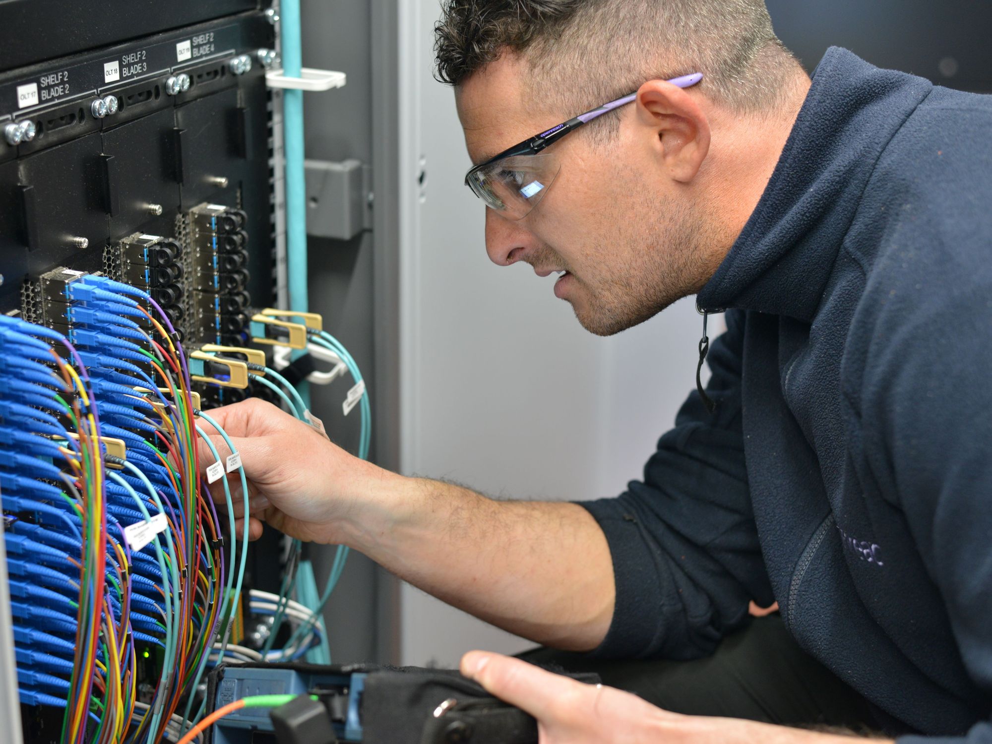 engineer fits cables into a cabinet to connect broadband