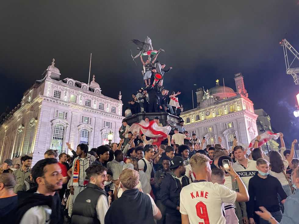 England football fans climb the statue of Eros in Piccadilly Circus, central London, after England beat Ukraine 4-0 in their Euro2020 quarter final match. Picture date: Saturday July 3, 2021.