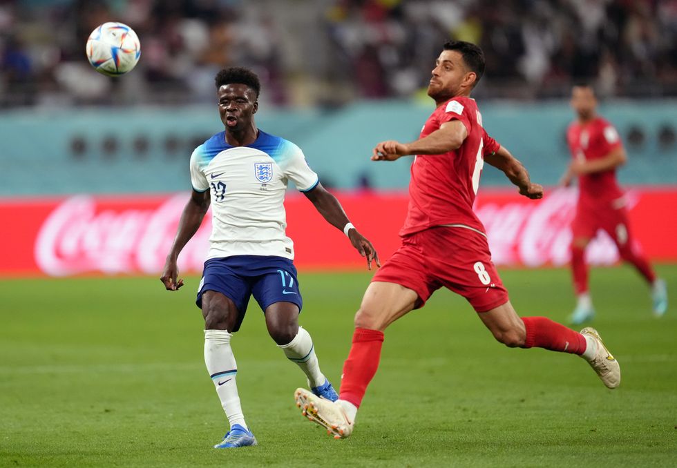 England's Bukayo Saka (left) and Iran's Morteza Pouraliganji battle for the ball during the FIFA World Cup Group B match at the Khalifa International Stadium, Doha. Picture date: Monday November 21, 2022.