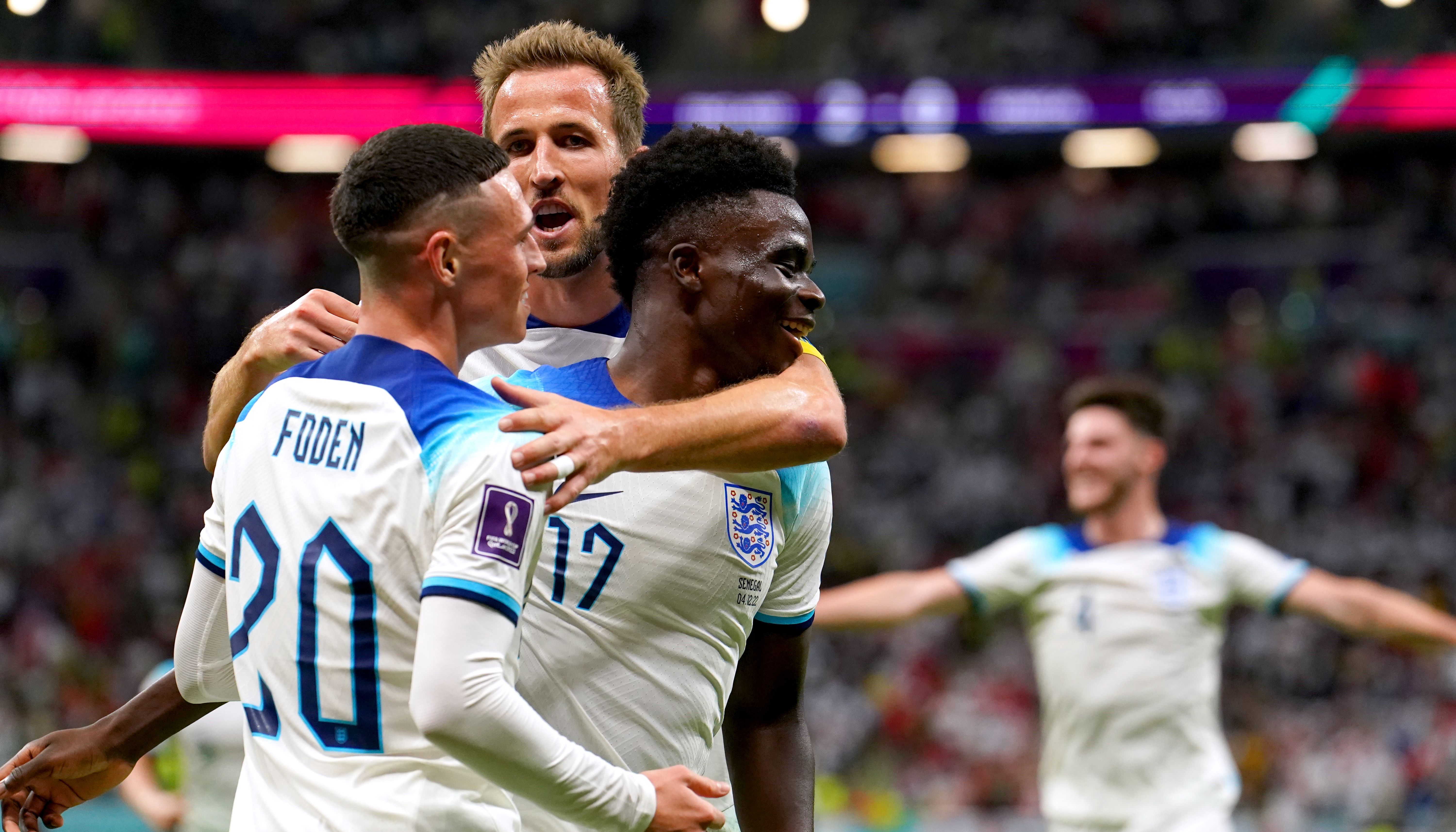 England's Bukayo Saka (right) celebrates with team-mates Phil Foden and Harry Kane after scoring their side's third goal of the game during the FIFA World Cup Round of Sixteen match at the Al-Bayt Stadium in Al Khor, Qatar.