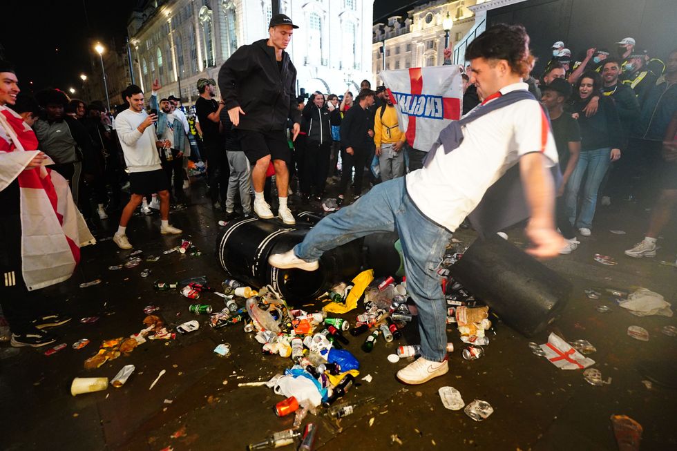 English fans kick and stand on a litter bin in Piccadilly Circus, London, after Italy beat England on penalties to win the UEFA Euro 2020 Final.