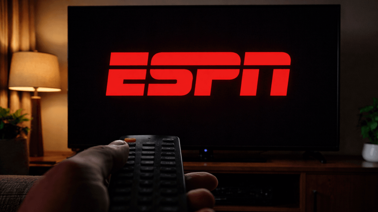 ESPN logo on TV with hand holding remote