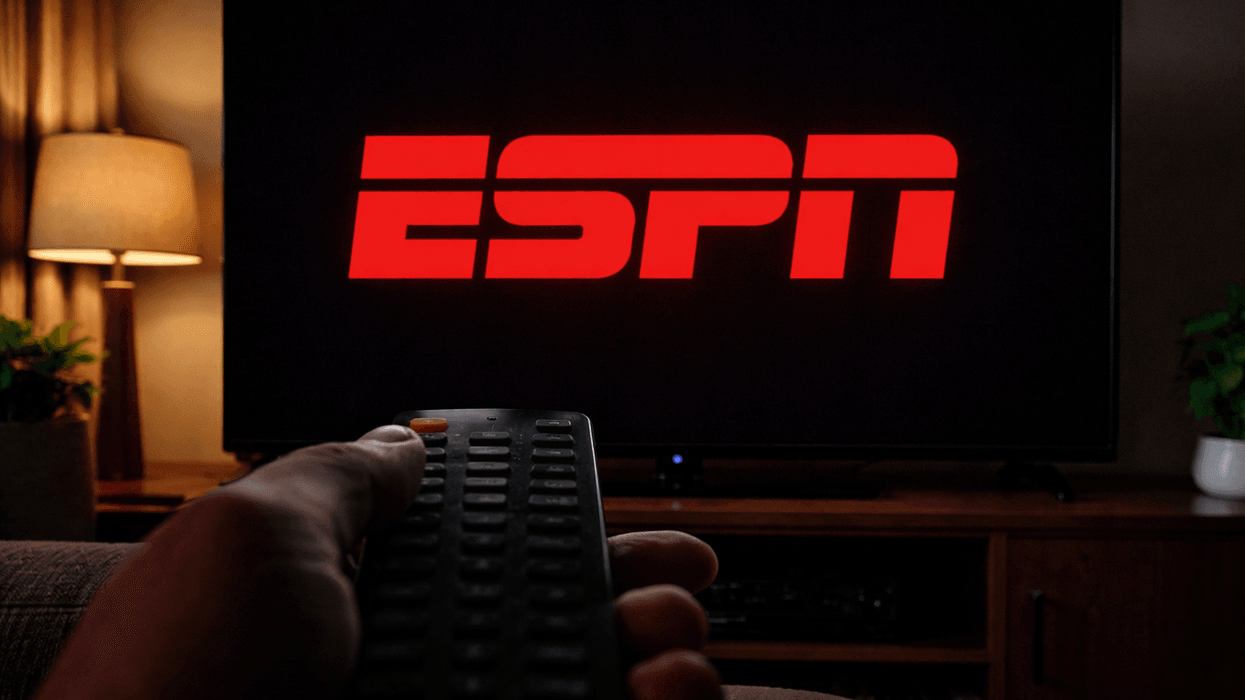 ESPN logo on TV with hand holding remote