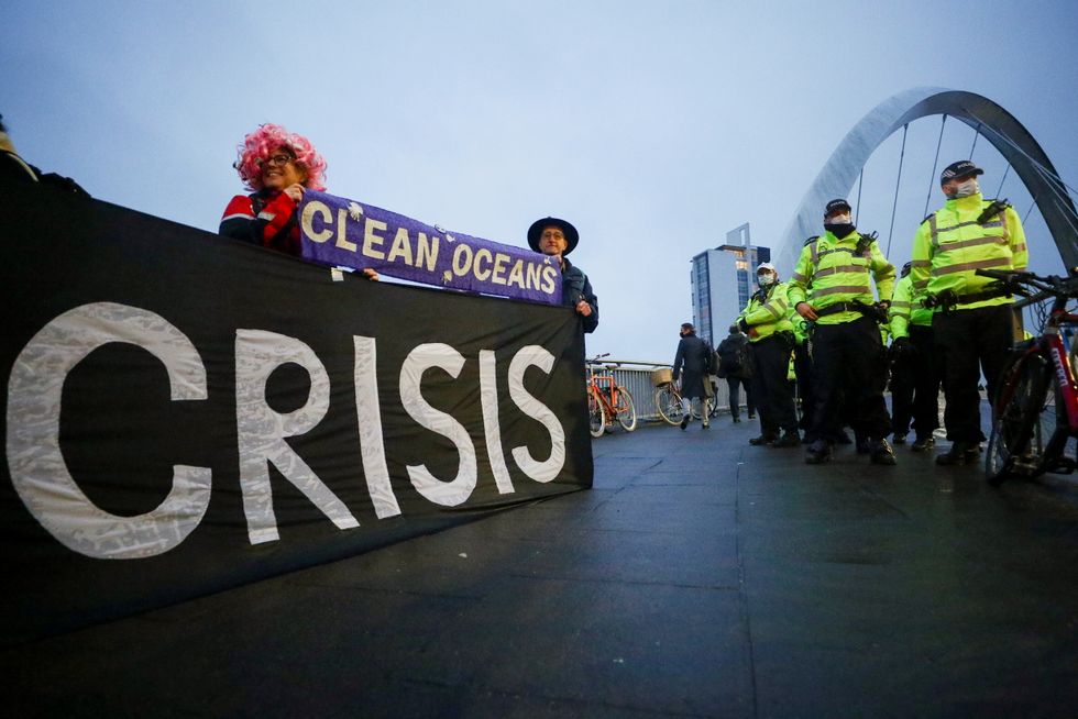 Extinction Rebellion activists hold a banner next to police officers during a protest outside the venue of the COP26