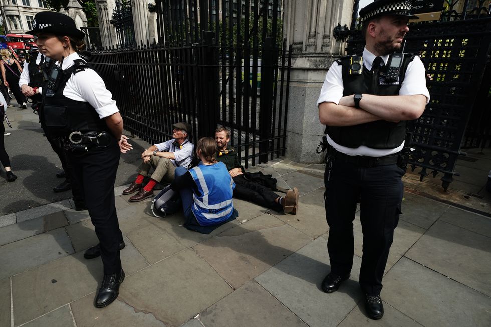Extinction Rebellion protesters, who have padlocked their necks to the railings, outside the Houses of Parliament, Westminster, calling for a Citizen's assembly. The campaign group says supporters have also superglued themselves around the Speaker's chair in the House of Commons chamber. Picture date: Friday September 2, 2022.