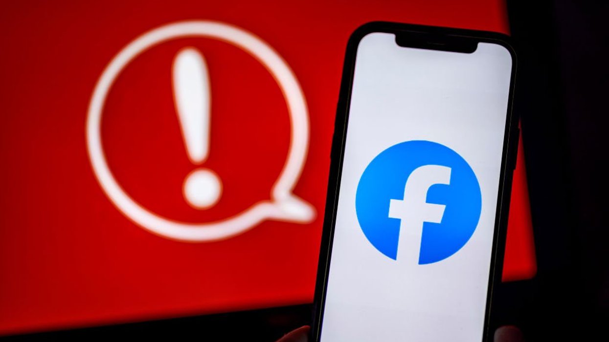 Facebook logo on mobile in front of red warning symbol