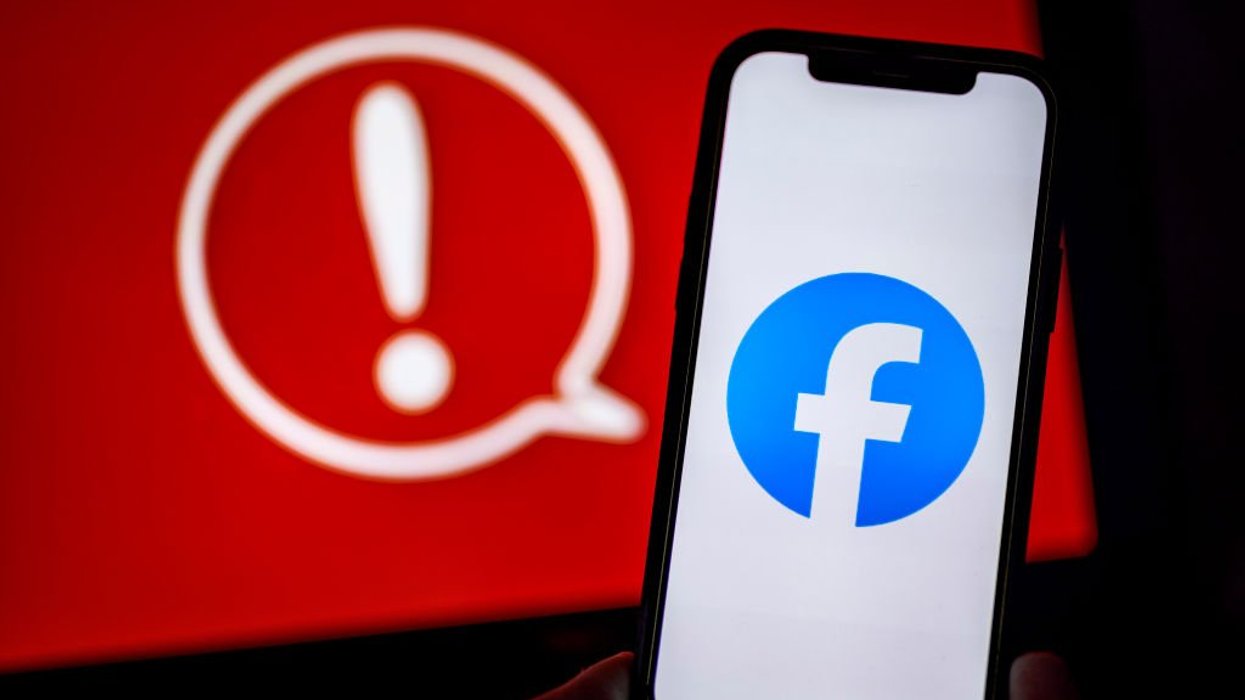 Facebook logo on mobile in front of red warning symbol