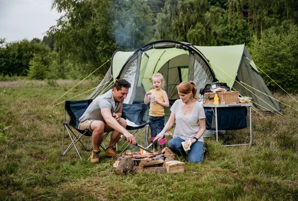 Family camping with tent and log fire