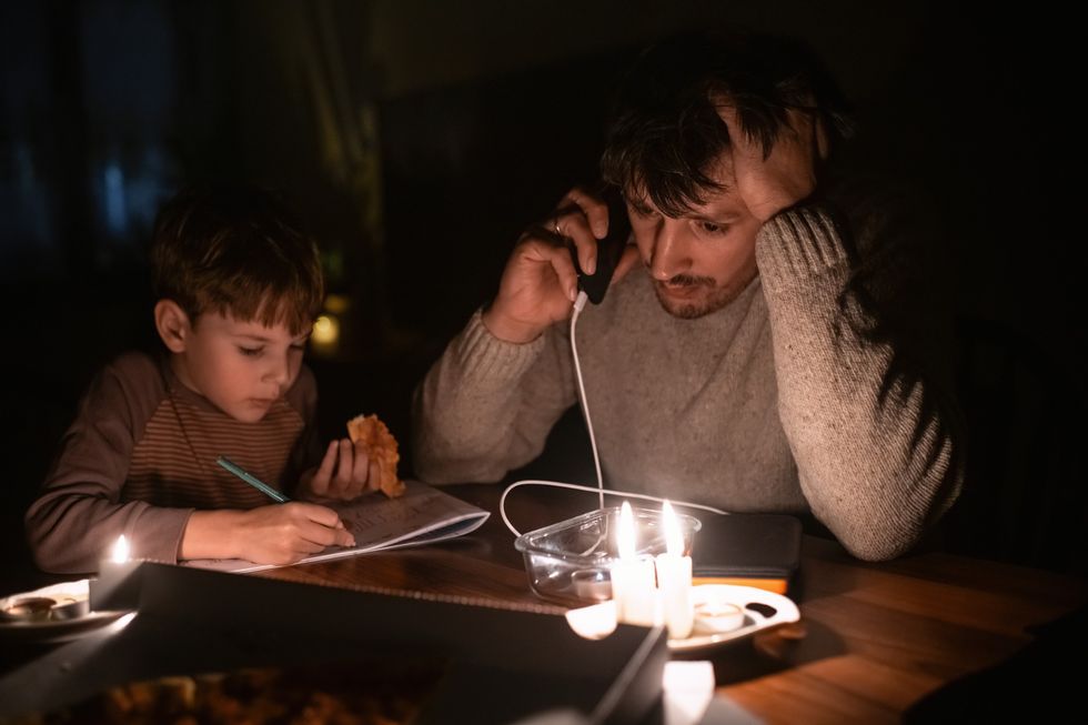 Family sitting at home with candles and eating pizza during blackout