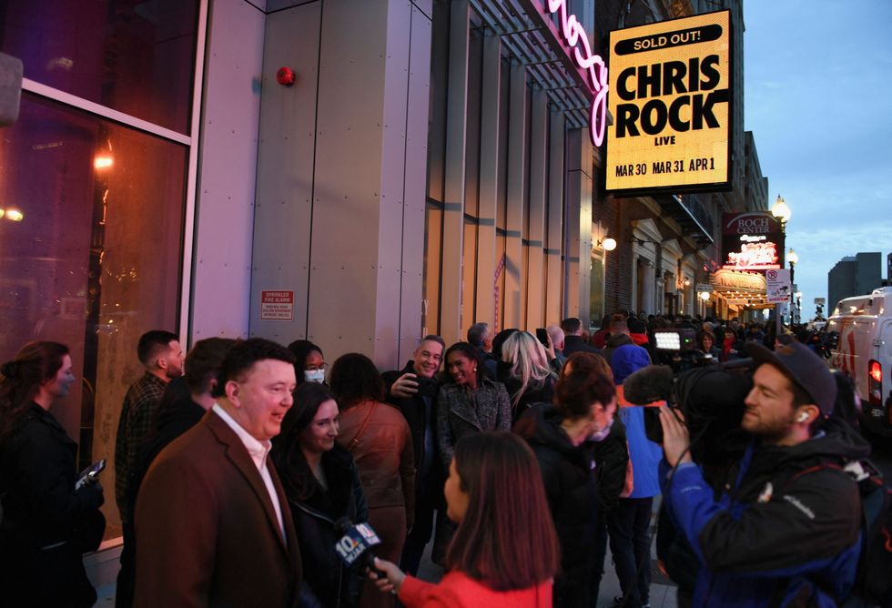 Fans are interviewed by members of the media as they wait in line outside the Wilbur Theater ahead of a performance by actor and comedian Chris Rock, his first performance since being hit by Will Smith at the Oscars, in Boston, Massachusetts, U.S., March 30, 2022. REUTERS/Amanda Sabga