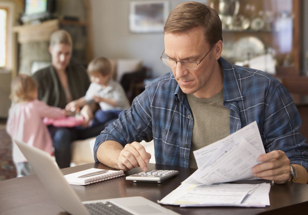 Father going over finances while family sits behind him