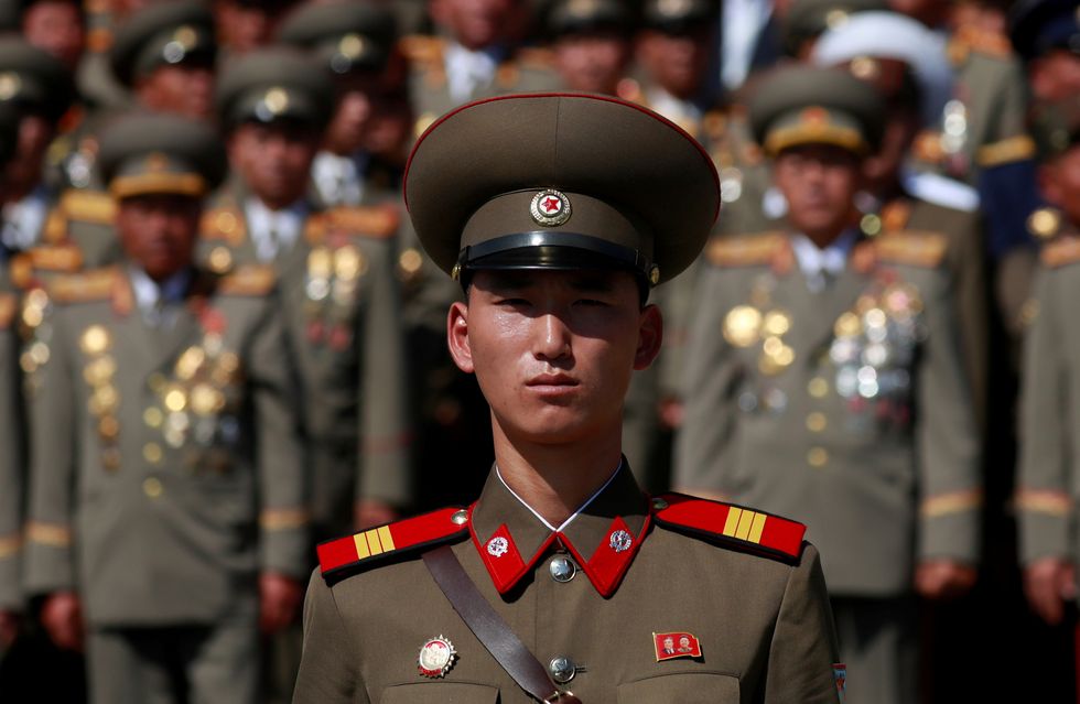 FILE PHOTO: A soldier wears a badge with portraits of late North Korean leaders Kim Il Sung and Kim Jong Il as he attends a military parade marking the 70th anniversary of North Korea's foundation in Pyongyang, North Korea, September 9, 2018. REUTERS/Danish Siddiqui/File Photo