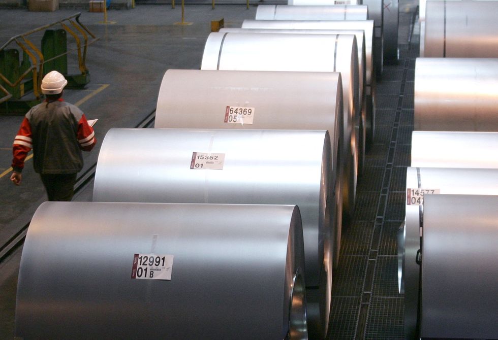 FILE PHOTO: A worker walks past reels of steel at an Arcelor steel plant in Florange near Metz in the French Lorraine region February 9, 2006. REUTERS/Vincent Kessler/File Photo