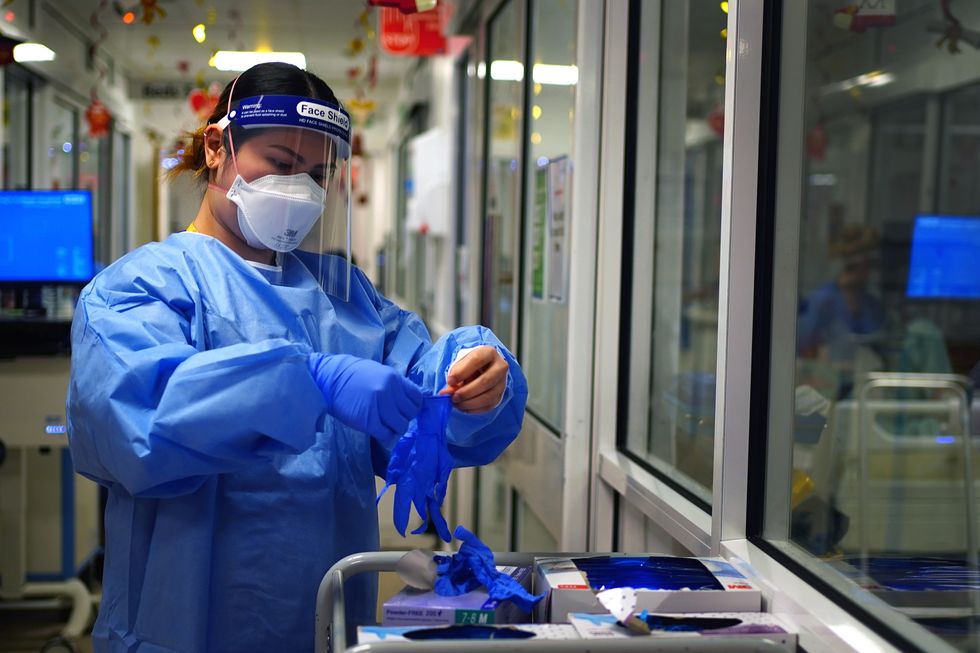 File photo dated 21/12/2021 of a nurse puts on PPE in a ward for Covid patients. Issue date: Wednesday March 30, 2022.