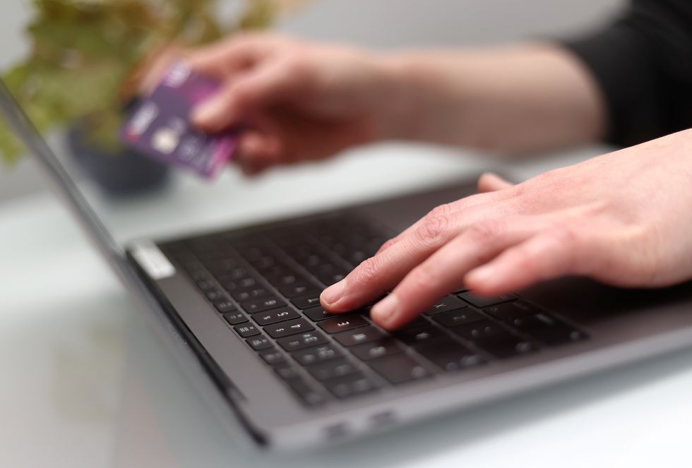 File photo dated 30/03/20 of a woman using a laptop as she holds a bank card. A big proportion of consumers have turned to financial tools like credit cards and overdrafts to help supplement their income amid cost-of-living pressures, according to a new survey.
