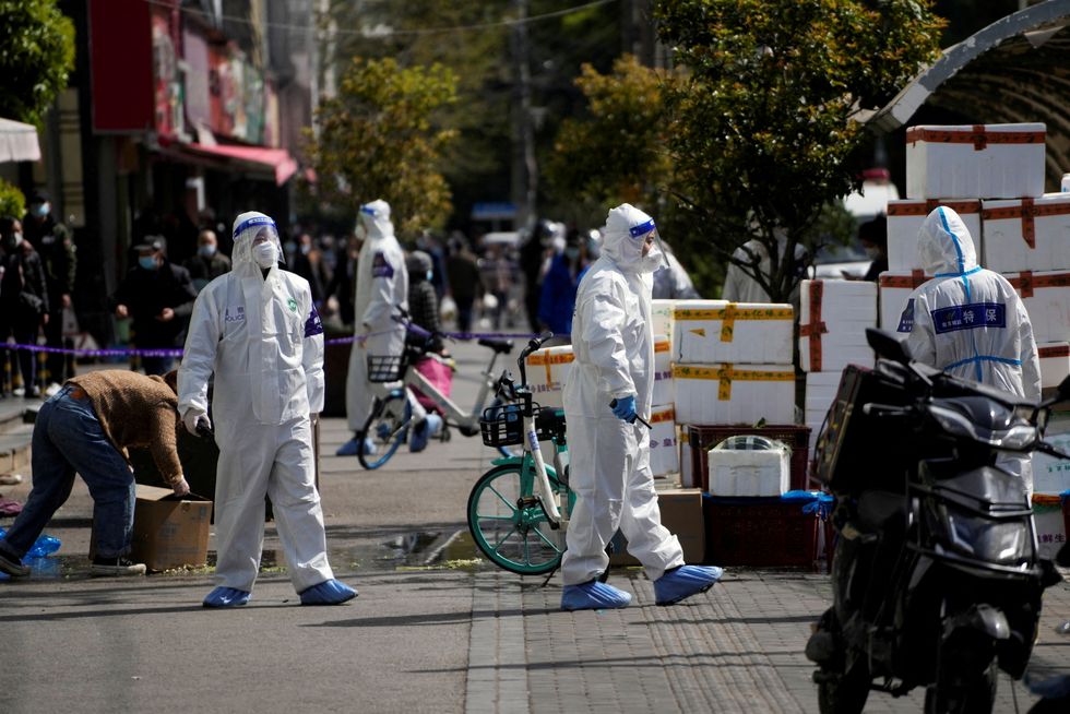 FILE PHOTO: Police and security members in protective suits stand outside cordoned off food stores following the coronavirus disease (COVID-19) outbreak in Shanghai, China March 29, 2022. REUTERS/Aly Song/File Photo