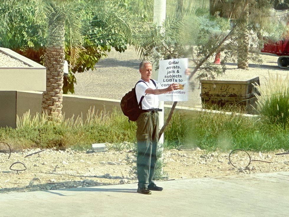 FILE PHOTO: Veteran British LGBTs rights campaigner Peter Tatchell, holds a sign in front of the National Museum of Qatar reading %22Qatar arrests, jails & subjects LGBTs to 'conversion' #QatarAntiGay%22, in Doha, Qatar, October 25, 2022. REUTERS/Obtained by Reuters/File Photo