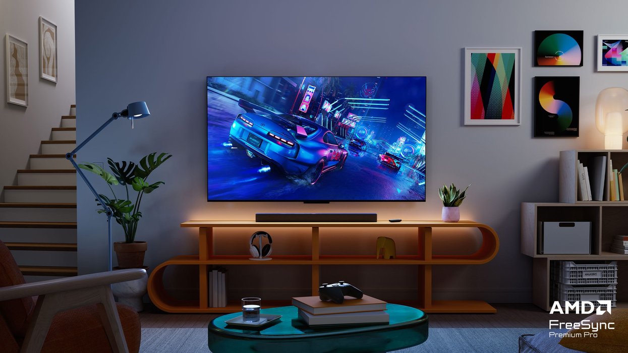fire tv omni mini-led tv on a media unit with a video game controller pictured on a coffee table